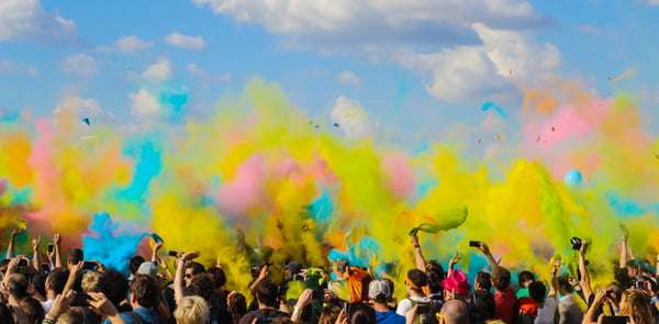A_crowd_at_a_concert_with_colorful_smoke_bombs_floating_above_them.jpg
